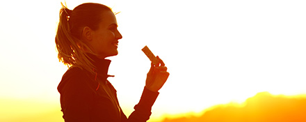 Woman eating a granola bar at sunrise