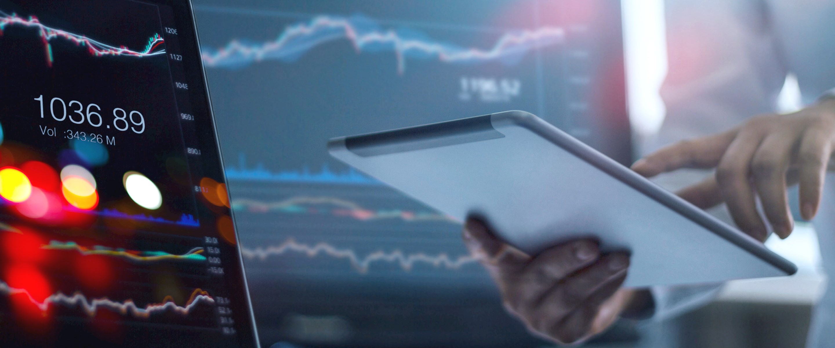 Someone holding a tablet in front of a computer screen