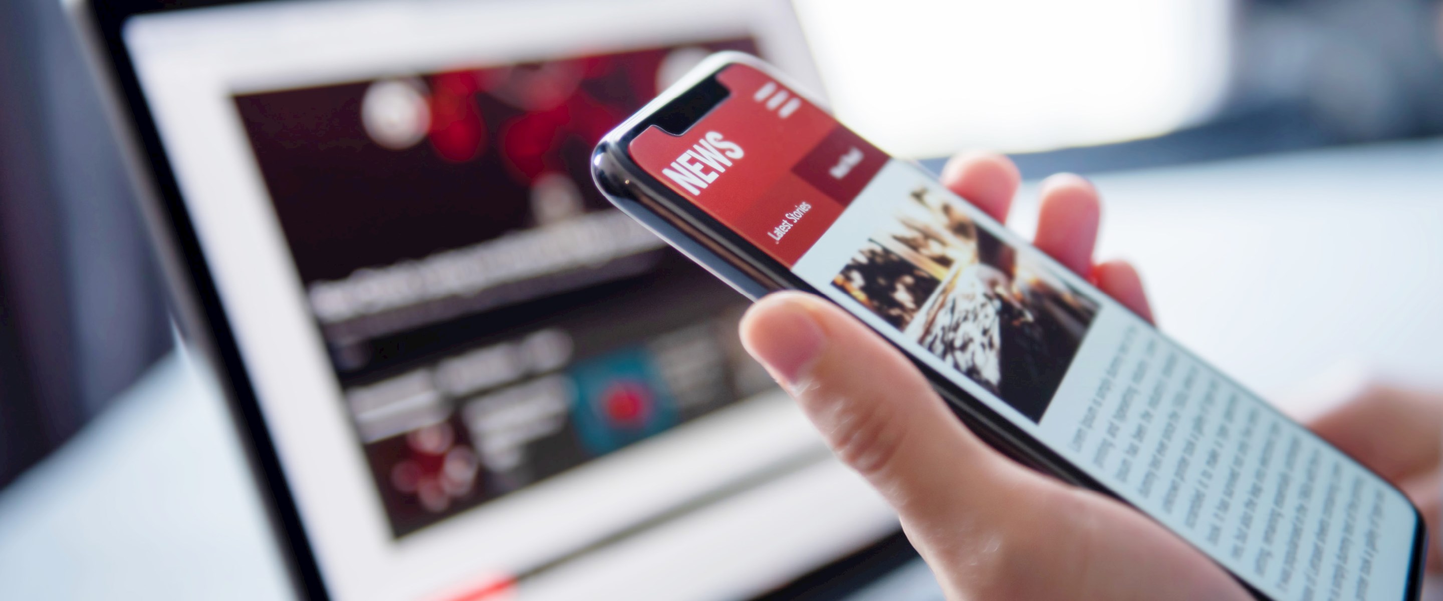 A hand holding a smartphone in front of a laptop