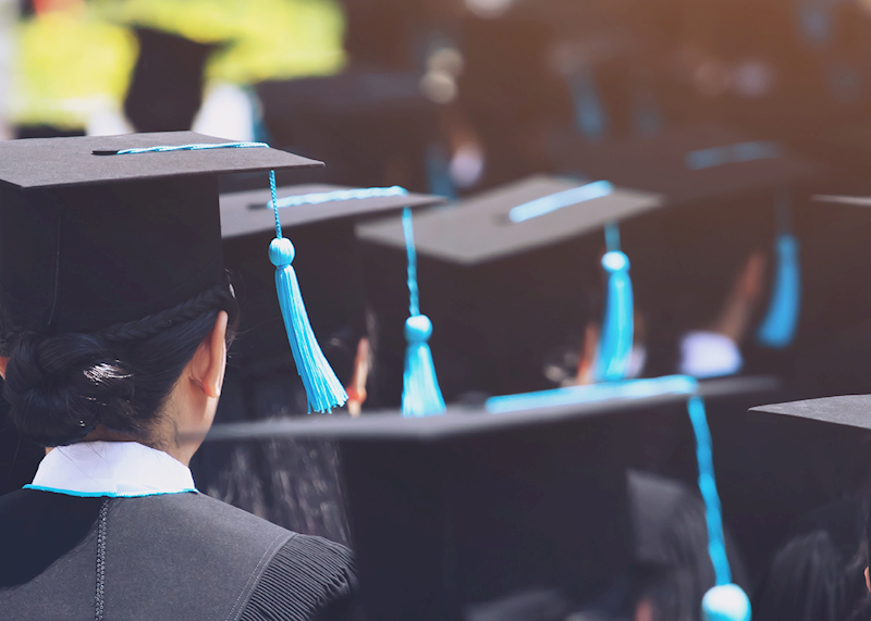 Back of students' heads wearing caps and gowns