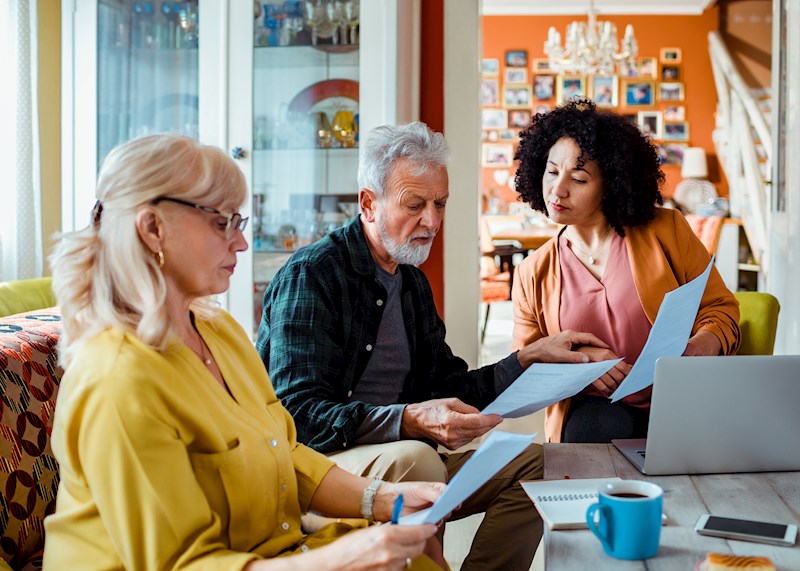 Three people sitting around a table looking at papers